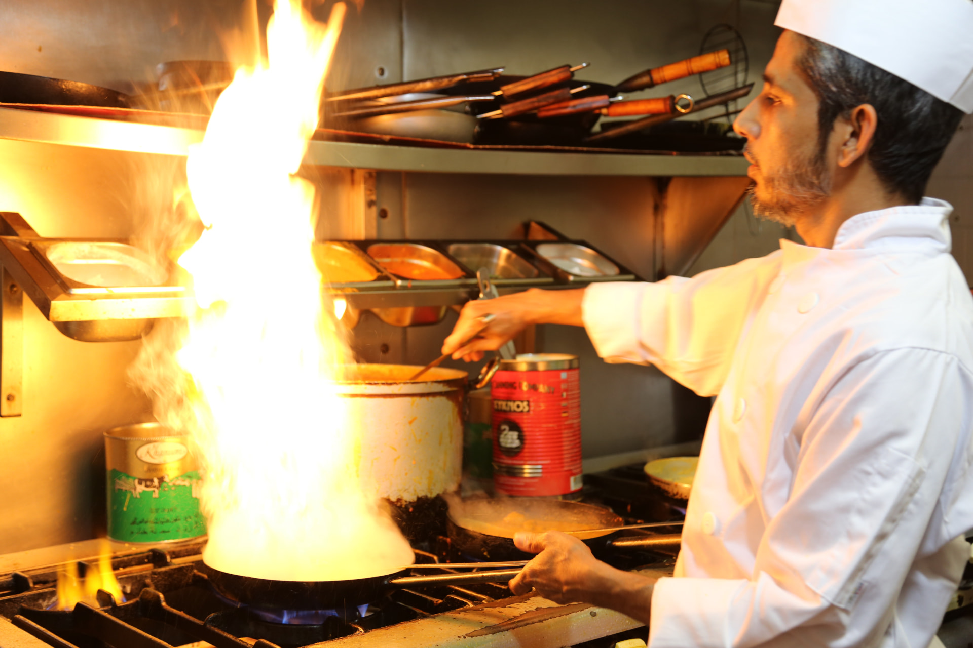 Photograph 2 of 6: Chef finishing a curry over an open flame in the Jaflong Tandoori kitchen