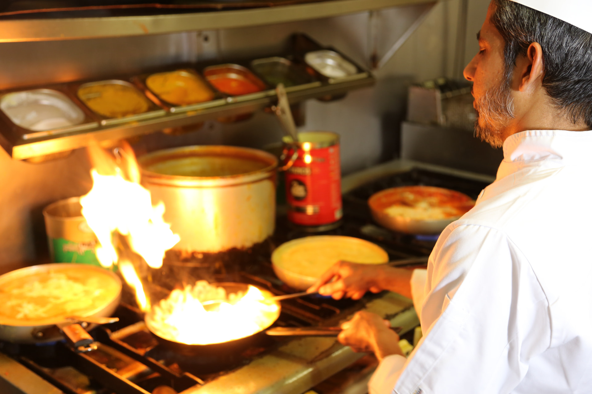 Photograph 3 of 6: Chef working several pans at once during evening service at Jaflong Tandoori